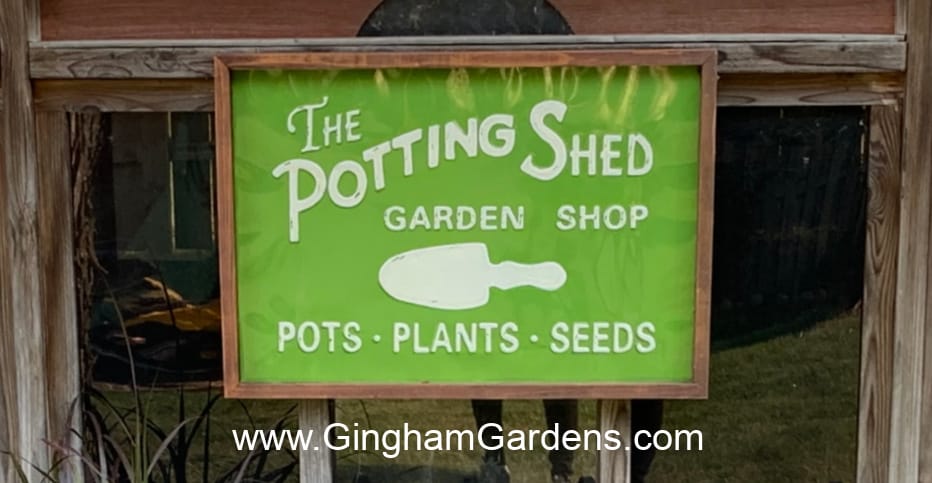 A garden sign that says The Potting Shed Garden Shop Pots Plants Seeds