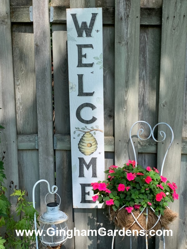 Image of a vertical Welcome sign in a garden.
