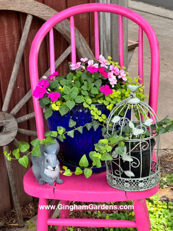 Bright pink chair with pot of flowers sitting on it.