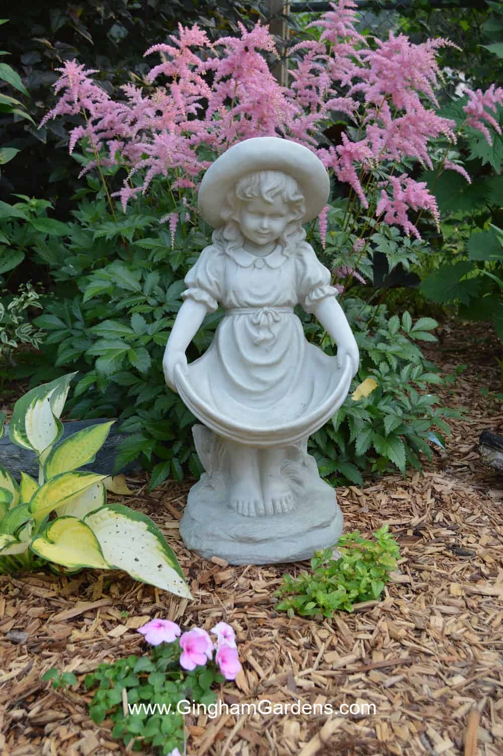 Girl garden statue with pink astilbe.