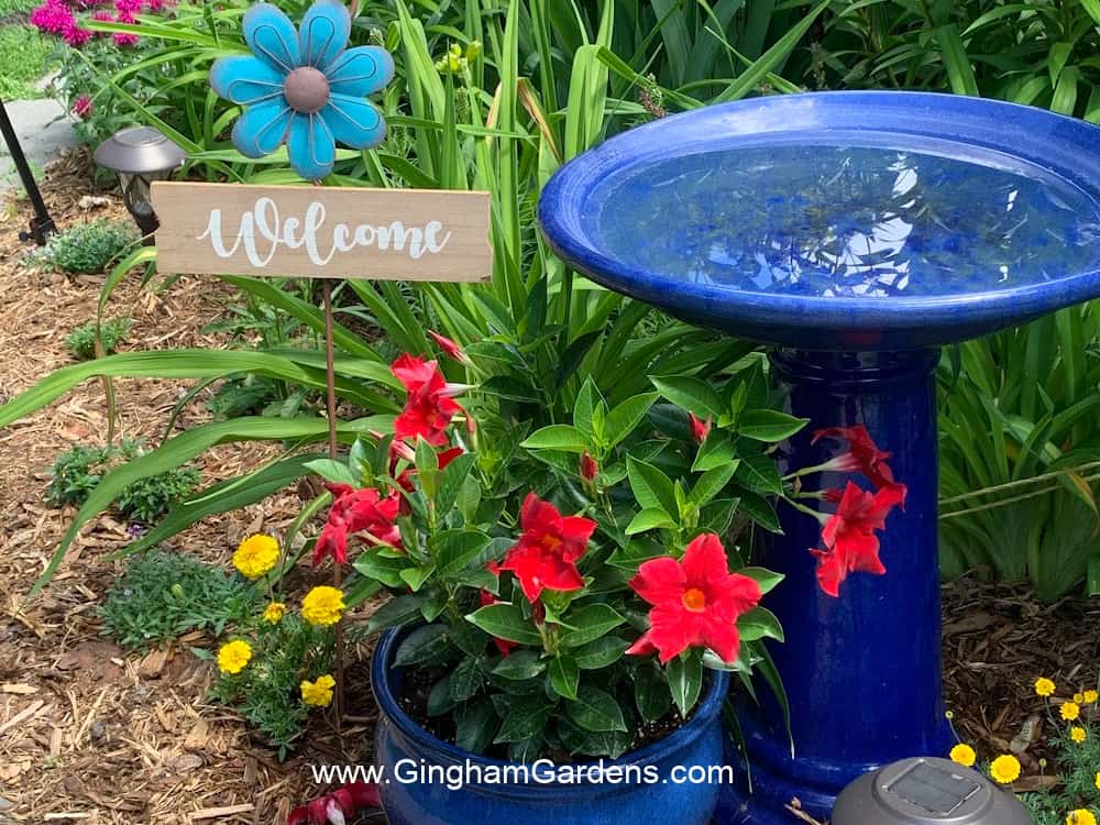 Cobalt blue bird bath and planter in a flower garden.