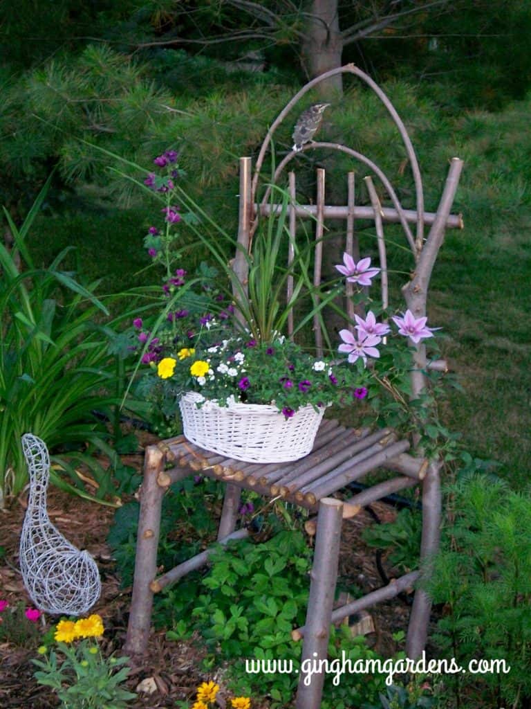 Chair made from maple branches in a flower garden.