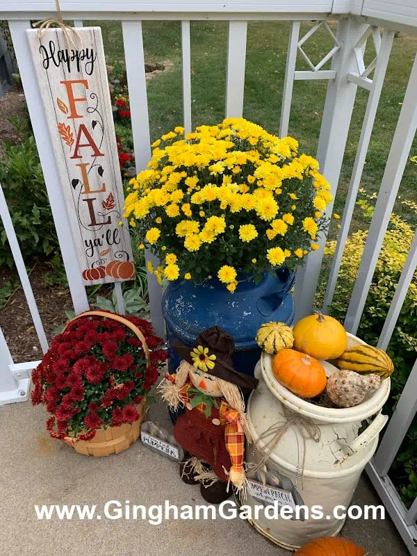 Front porch fall decorations with flowers, pumpkins and a happy fall sign