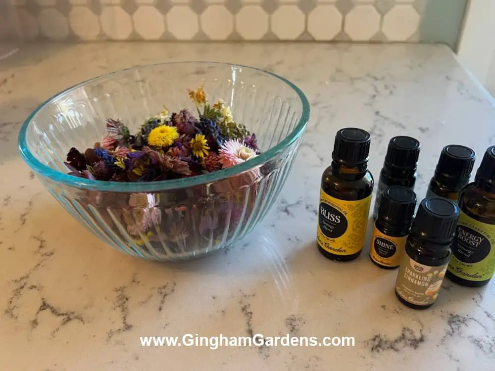 Dried flowers in a bowl and bottles of essential oils for making potpourri.