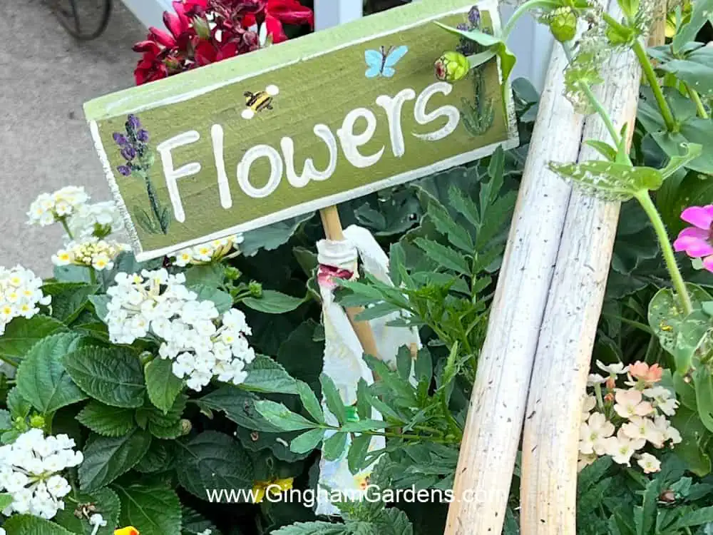 Garden stake spelling out the word "flowers" in a basket of flowering plants.