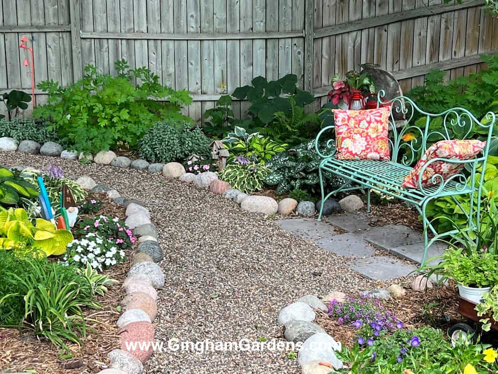 Shade garden with a lovely gravel path lined with fieldstones and a garden bench.
